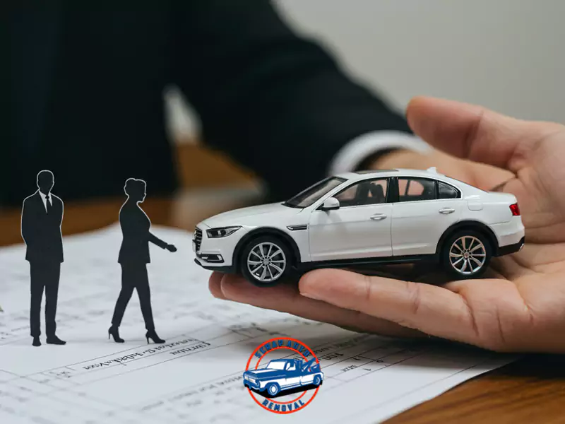A hand holding a white model car, with two silhouetted figures on a contract, and the Scrap Auto Removal logo.