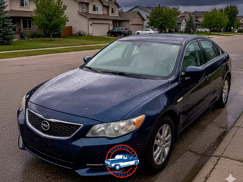 Dark blue sedan parked on a suburban street curb on a rainy day, showing water droplets and clean paint.